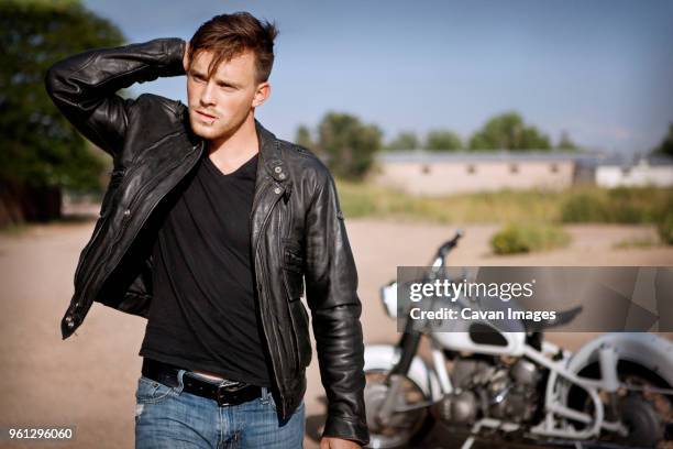 young man standing on field with motorcycle in background - toothpick stock pictures, royalty-free photos & images