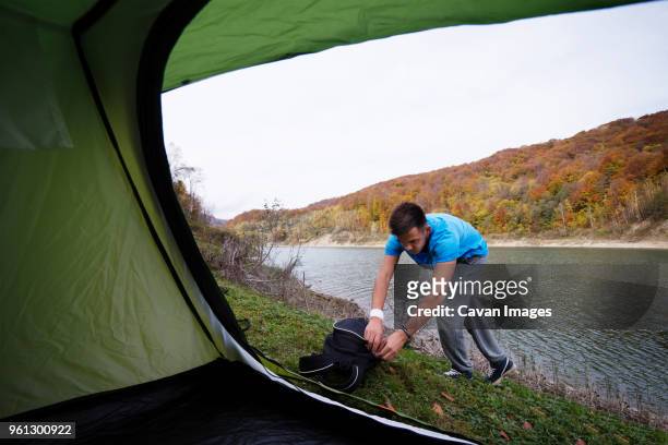 man opening backpack by river - open backpack stock pictures, royalty-free photos & images