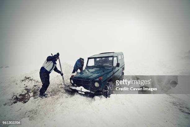 men removing snow with shovel by car - bloccato foto e immagini stock