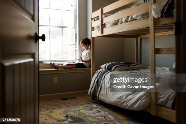 boy with book and felt tip pens sitting on window sill - felt tip pen stock-fotos und bilder