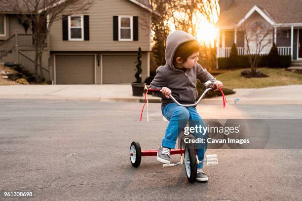 boy wearing hooded jacket while sitting on tricycle - tricycle stock pictures, royalty-free photos & images