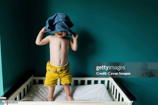 boy removing shirt while standing in bunkbed against wall - bunk beds for 3 ストックフォトと画像