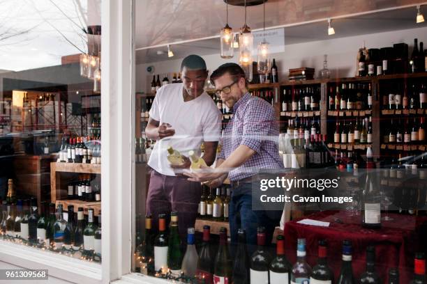 multi-ethnic colleagues discussing in wine shop - vitrinekast stockfoto's en -beelden