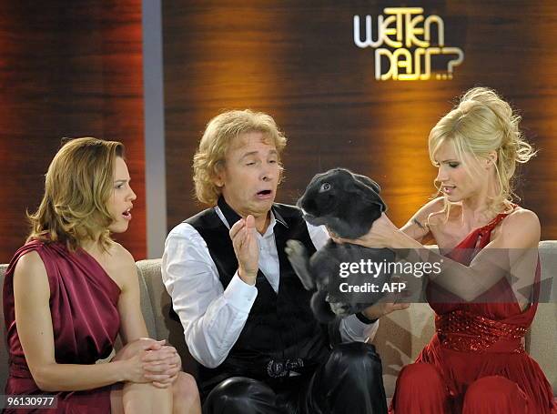 Swiss TV host Michelle Hunziker holds a rabbit next to German showmaster Thomas Gottschalk and US actress Hilary Swank during the 186th edition of...