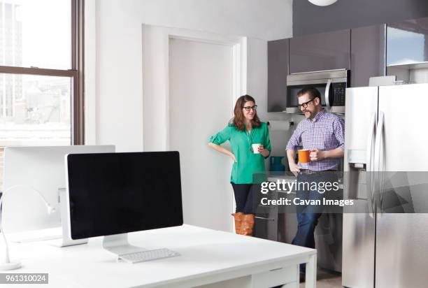 creative business colleagues holding coffee mugs while discussing in office - kaffee oder teepause stock-fotos und bilder