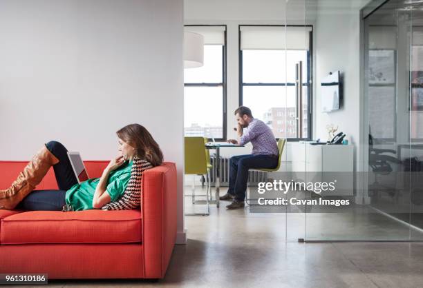 side view of business people working in creative office - red sofa stock pictures, royalty-free photos & images