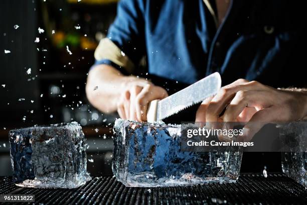 midsection of chef breaking ice block in kitchen - breaking the ice stock-fotos und bilder