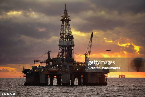 oil rigs in sea against cloudy sky sunset - gulf of mexico oil rig stock pictures, royalty-free photos & images