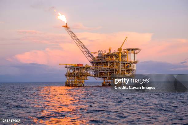 offshore platform in sea against sky during sunset - plataforma para la exploración de petróleo fotografías e imágenes de stock