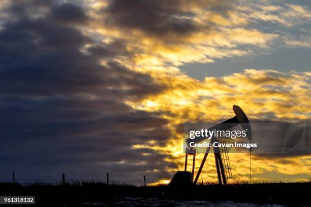 pumpjack at oil industry against cloudy sky during sunset - plataforma para la exploración de petróleo fotografías e imágenes de stock