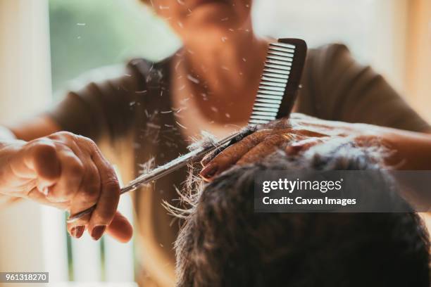 midsection of female barber cutting male customers hair - haar knippen stockfoto's en -beelden