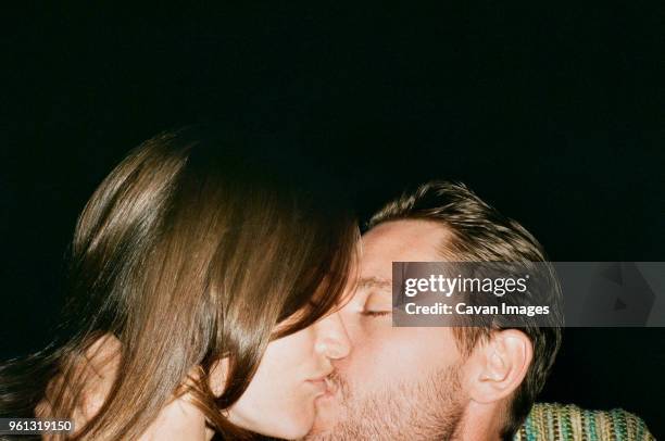 close-up of affectionate couple kissing against black background - amour fou photos et images de collection