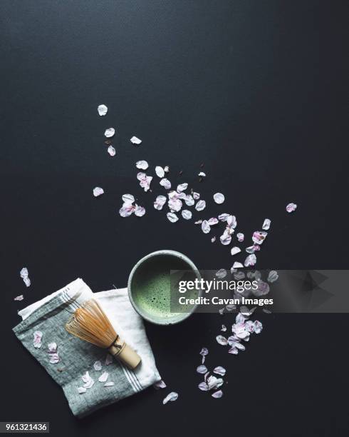 overhead view of matcha tea and bamboo whisk by petals on black background - black bamboo bildbanksfoton och bilder