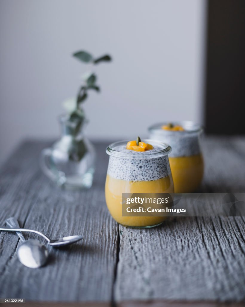 Jars of chia with mango pudding on wooden table