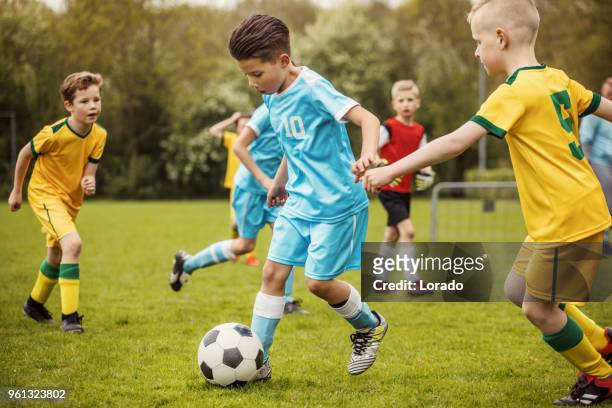 two boys soccer teams competing for the ball during a football match - match sport imagens e fotografias de stock