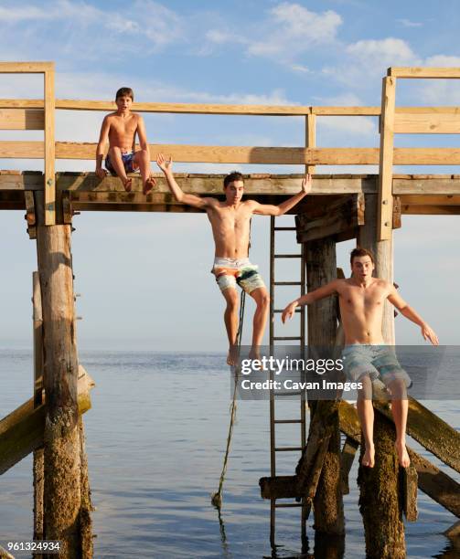 excited brothers diving into sea from pier - zwembroek stockfoto's en -beelden