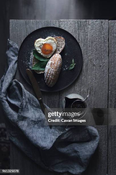 overhead view of heart shape sunny side up egg served with toasted breads on table - teesieb stock-fotos und bilder