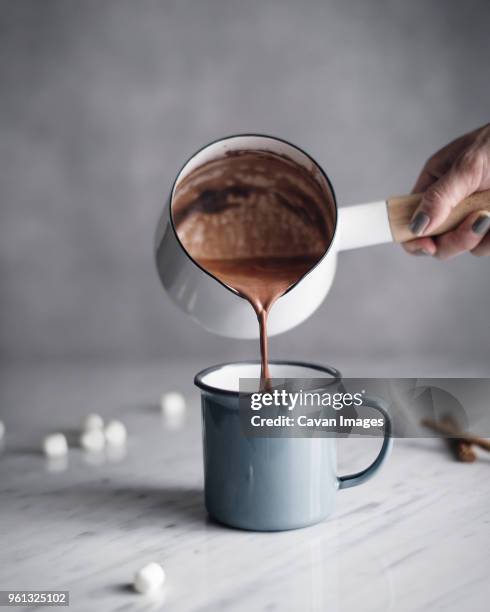 cropped image of woman pouring hot chocolate in mug on table - hot chocolate foto e immagini stock