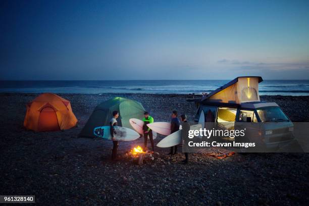 friends with surfboard camping at beach against sky - baja california photos et images de collection