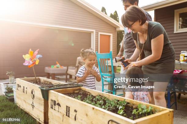 parents playing with daughters at backyard - two kids playing with hose stock pictures, royalty-free photos & images