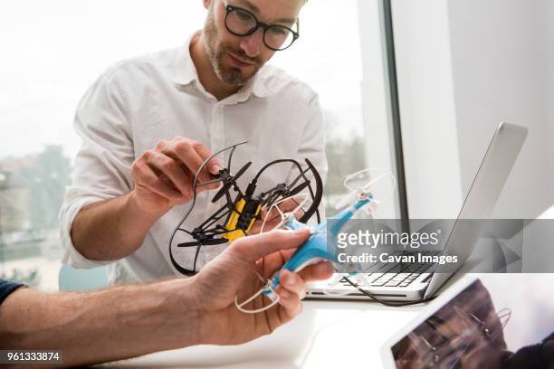 cropped hand of engineer with colleague making drones in office - nur erwachsene stock-fotos und bilder