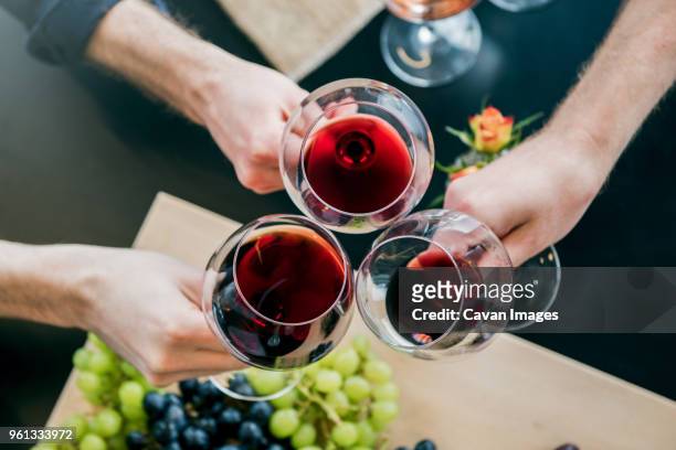 cropped hands of male friends toasting wine at tasting room - red wine foto e immagini stock