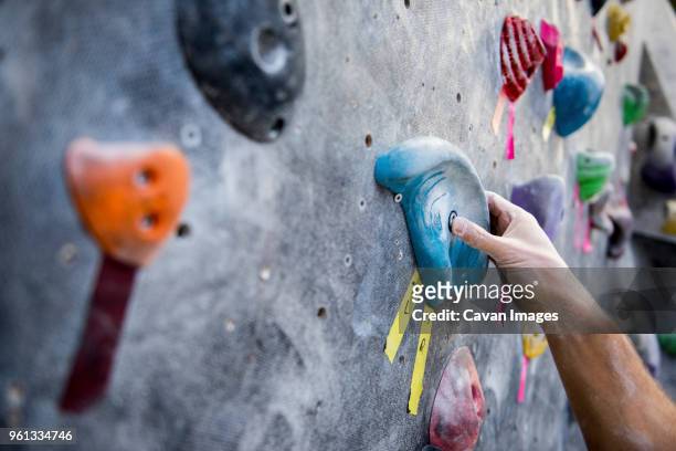 cropped image of athlete holding rock on climbing wall - indoor climbing stock-fotos und bilder