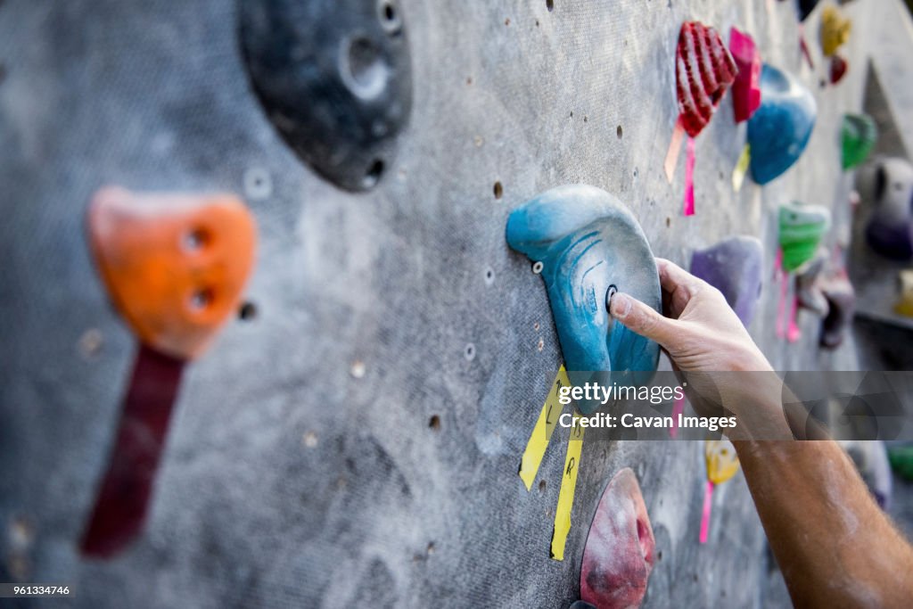 Cropped image of athlete holding rock on climbing wall