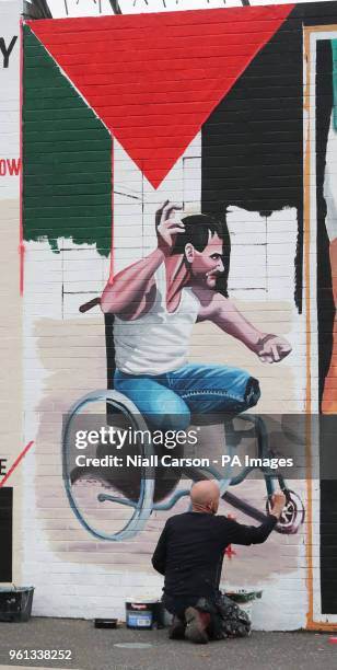 Belfast artist Marty Lyons paints a mural on the Falls Road of Palestinian Fadi Abu Salah, who lost his legs in 2008 in an airstrike and was killed...