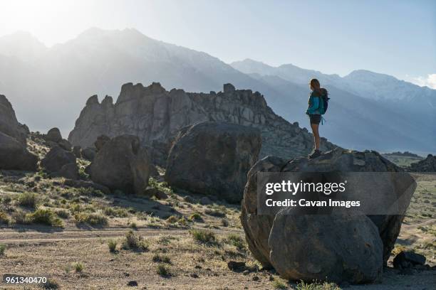 full length of female hiker looking at alabama hills while standing on rock - alabama lifestyles stock pictures, royalty-free photos & images