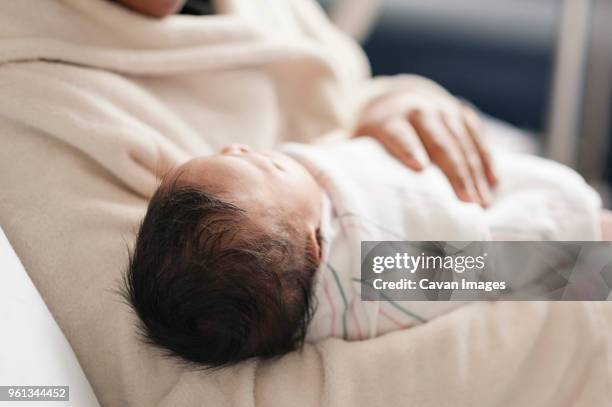 midsection of mother carrying newborn baby in hospital - emmitouflé dans une couverture photos et images de collection