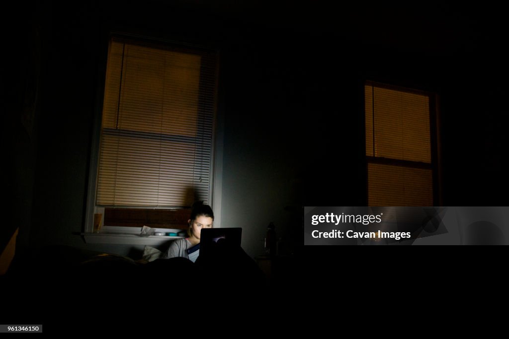 Woman using laptop computer in darkroom at home