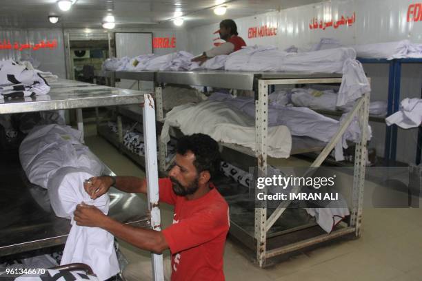 Pakistani volunteers adjust the dead bodies of heatwave victims at the Edhi Foundation morgue in Karachi on May 22, 2018. - Dozens of people are...