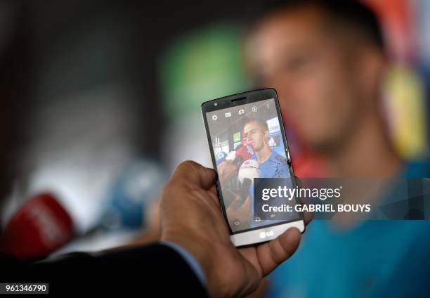 Person takes a photo with a smartphone as Real Madrid's Spanish midfielder Lucas Vazquez addresses journalists during Real Madrid's Media Open Day...