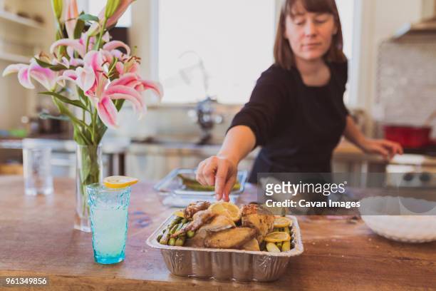 woman reaching for lemon slice on chicken meat at table - lemon chicken stock pictures, royalty-free photos & images