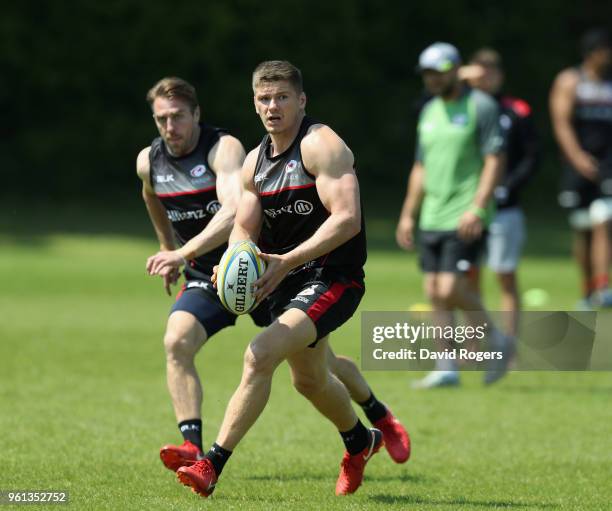 Owen Farrell runs with the ball with team mate Chris Wyles in support during the Saracens training session held at Old Albanians on May 22, 2018 in...