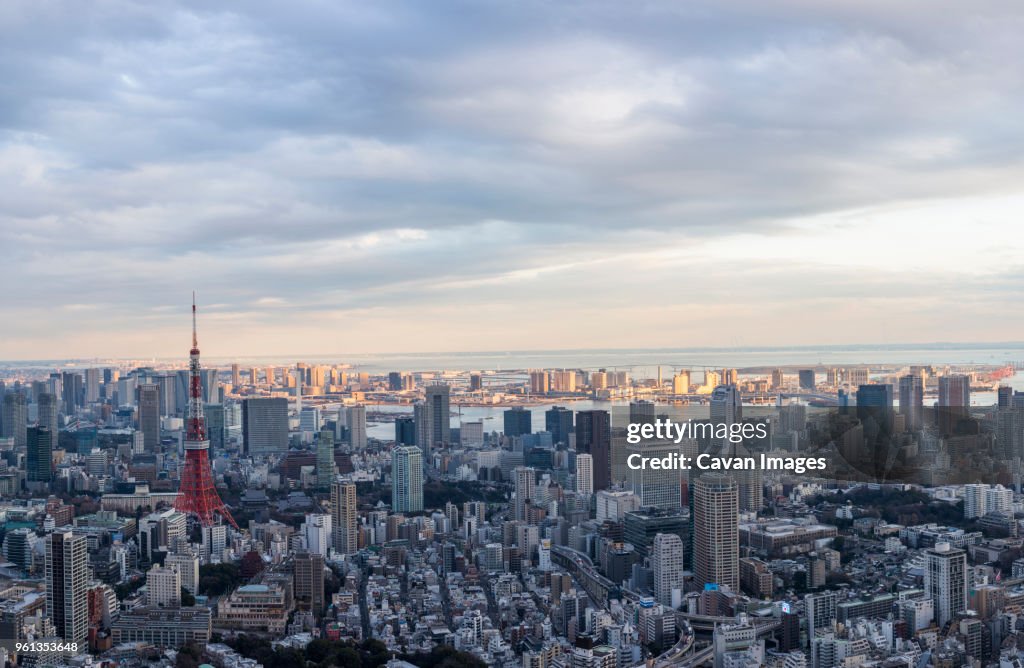 Aerial view of Tokyo Tower amidst city against cloudy sky