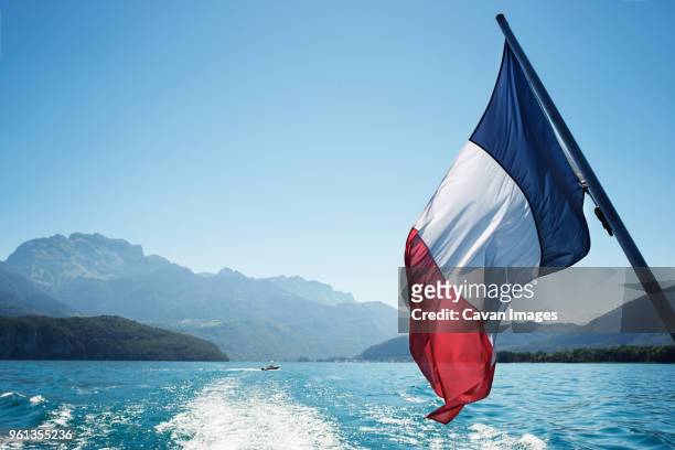 french flag over lake annecy against clear sky - bandera francesa fotografías e imágenes de stock