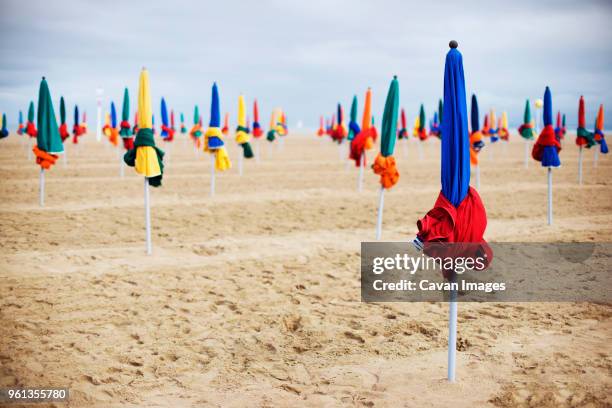 closed parasols on sand at beach - beach umbrella sand stockfoto's en -beelden