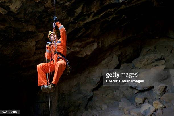 full length of athlete spelunking in cave - spelunking stockfoto's en -beelden