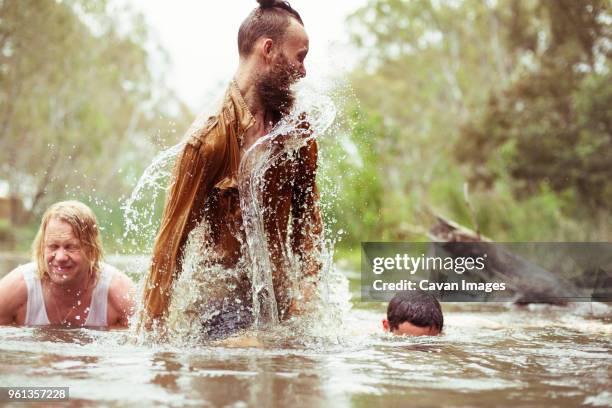 happy friends bathing in river at forest - river bathing imagens e fotografias de stock