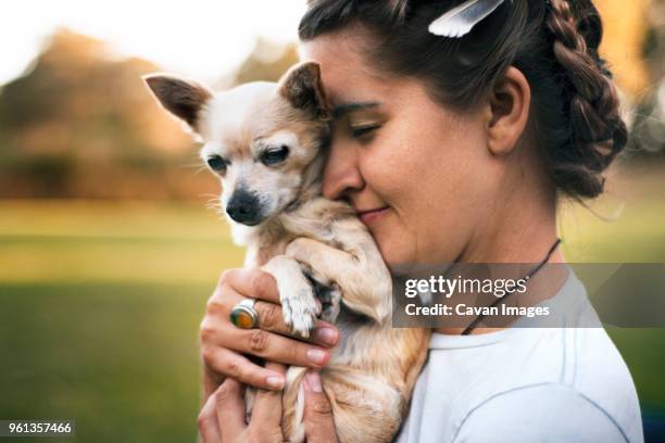 side view of smiling woman holding chihuahua on field - chihuahua love stock pictures, royalty-free photos & images