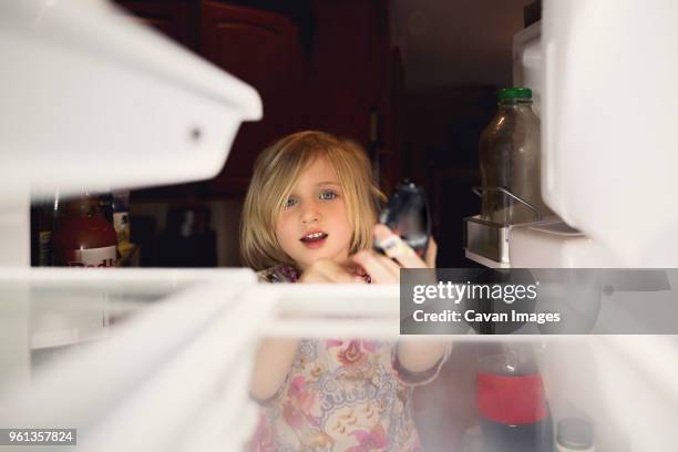 cute girl looking into refrigerator at home - refrigerator front stock pictures, royalty-free photos & images