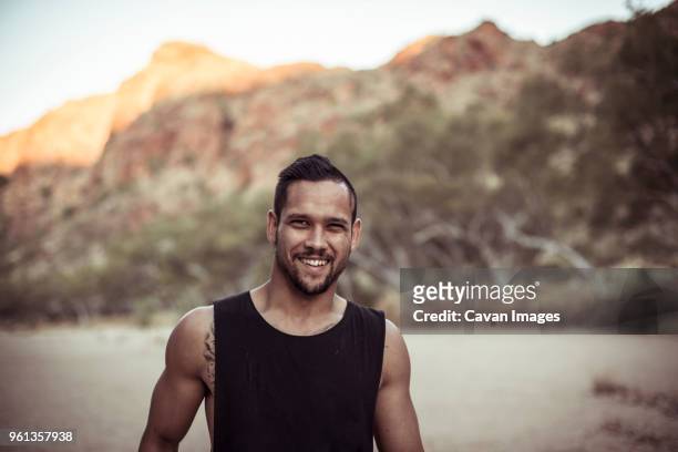 portrait of smiling man standing against mountain at desert - territorio del nord foto e immagini stock