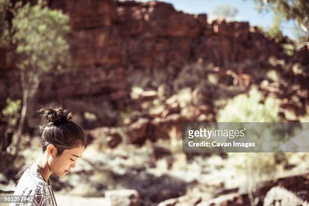 side view of woman standing by rock formations at desert during sunny day - northern territory stock pictures, royalty-free photos & images