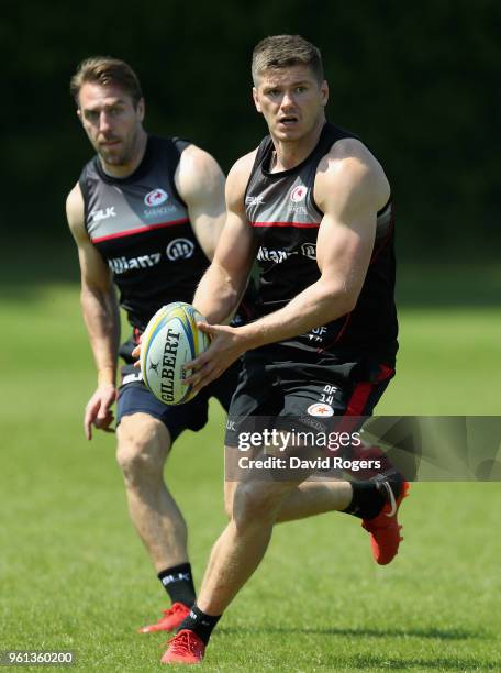 Owen Farrell runs with the ball with team mate Chris Wyles in support during the Saracens training session held at Old Albanians on May 22, 2018 in...