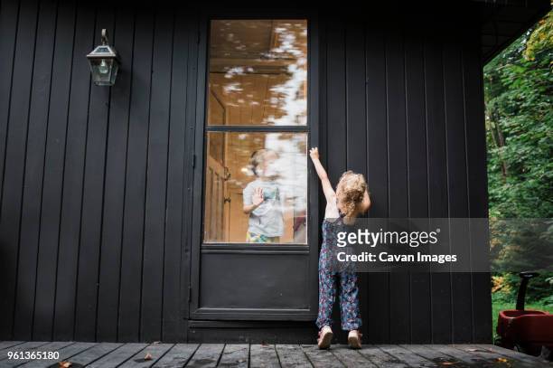 sister opening door from porch while brother standing inside house - family front door imagens e fotografias de stock