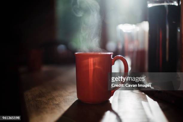 close-up of steam emitting from coffee cup on table at home - coffee steam stock pictures, royalty-free photos & images