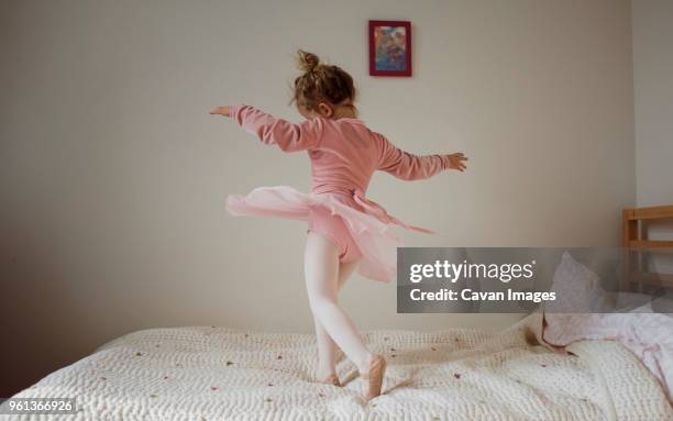 girl in ballet costume dancing on bed at home - danseres stockfoto's en -beelden