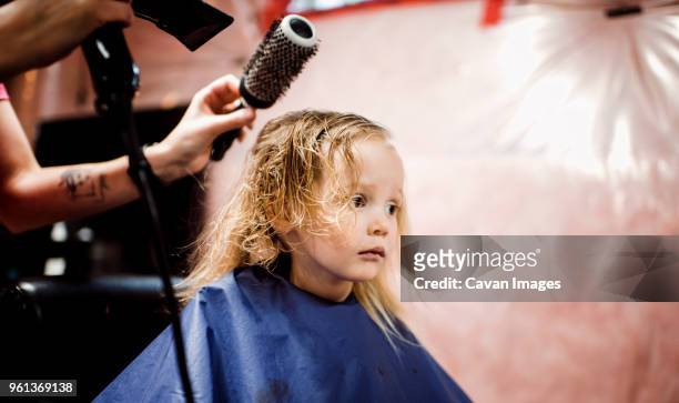 cropped hands of hairdresser using hair dryer on girl in salon - hand holding hair dryer stock pictures, royalty-free photos & images